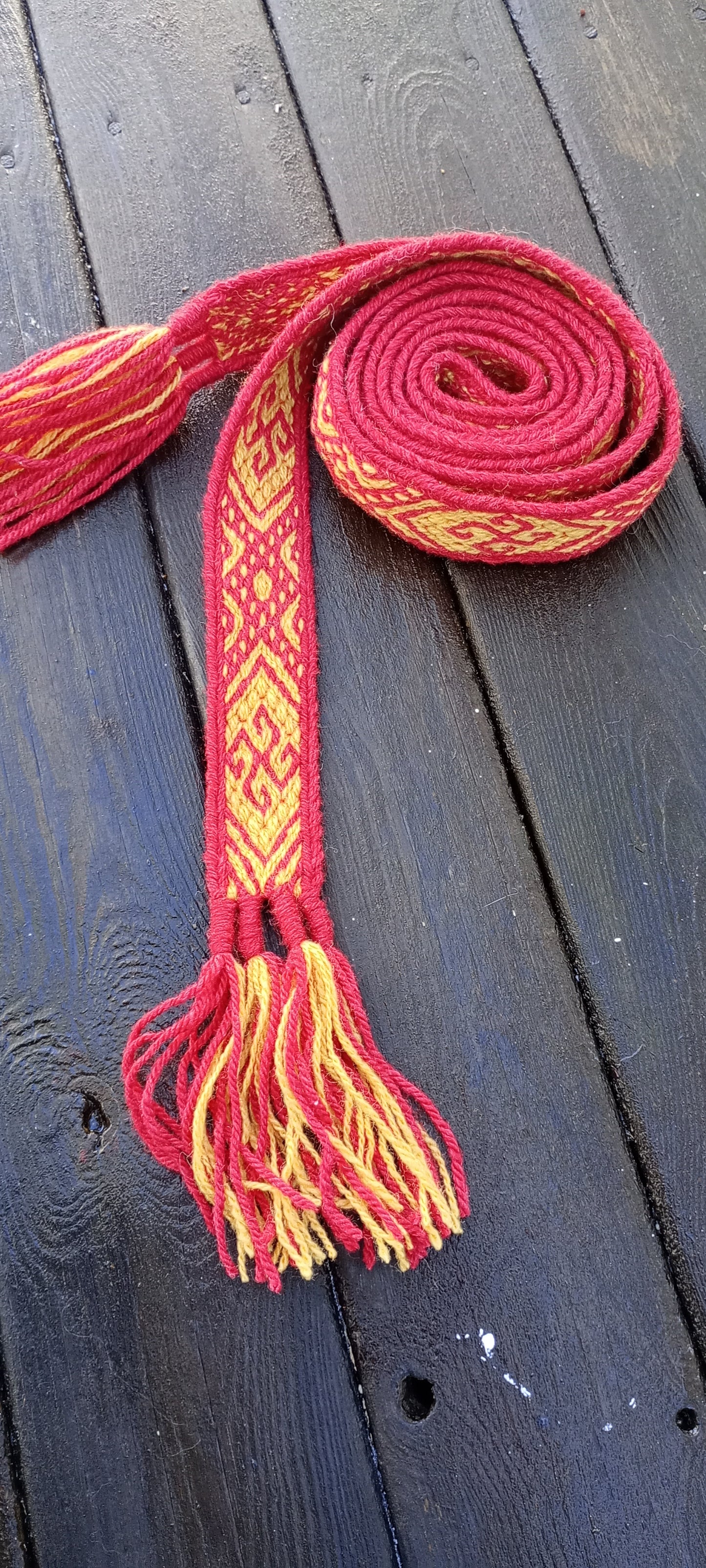 Red and yellow tablet woven belt with curly suncross motive